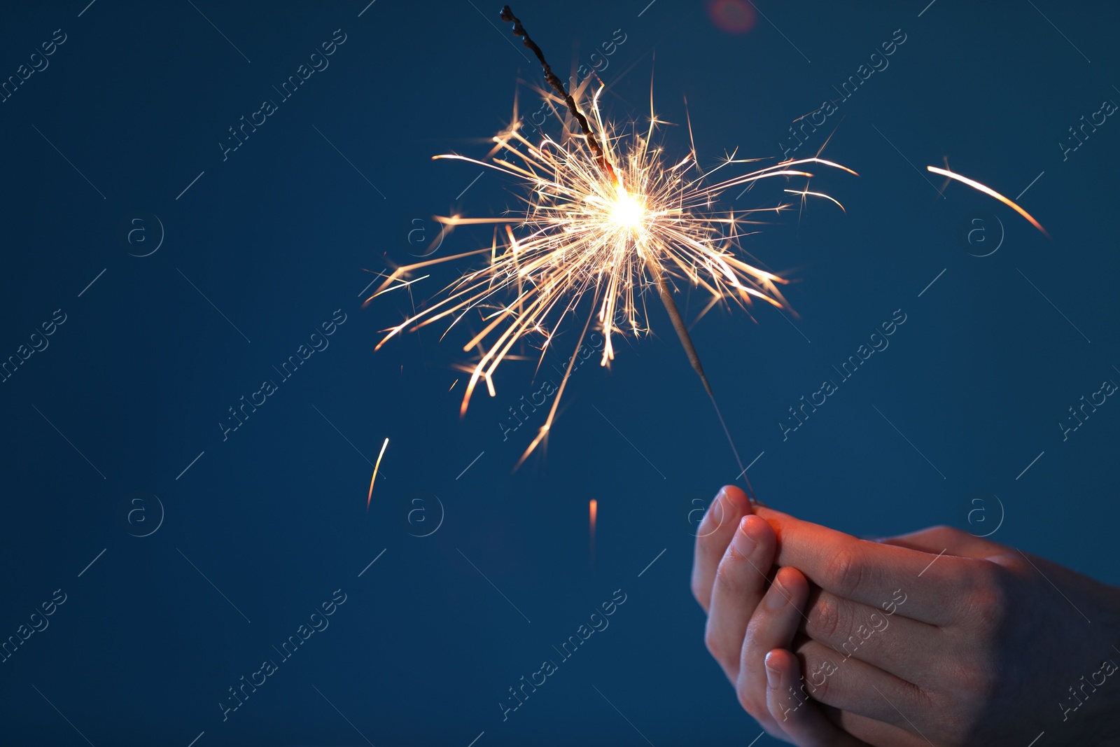 Photo of Man with bright burning sparkler on light blue background, closeup. Space for text