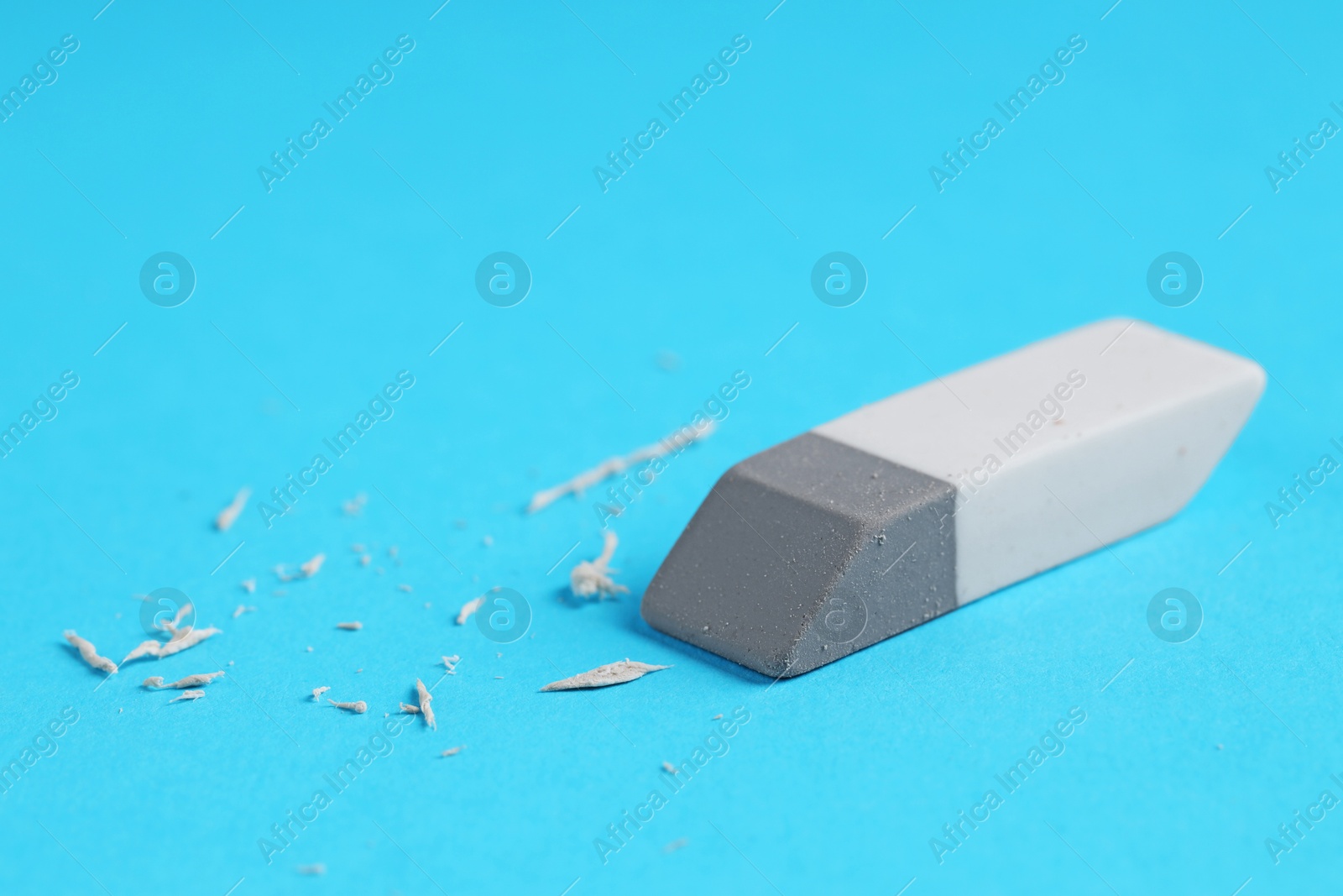 Photo of One eraser and scraps on light blue background, closeup