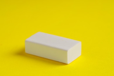 Photo of One eraser on yellow background, closeup view