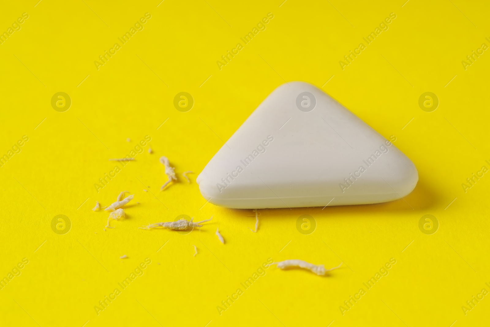 Photo of One eraser and scraps on yellow background, closeup