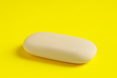 Photo of One eraser on yellow background, closeup view