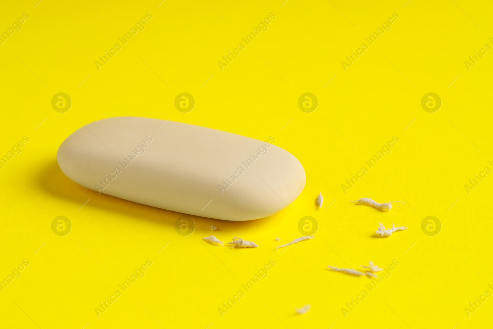 Photo of One eraser and scraps on yellow background, closeup