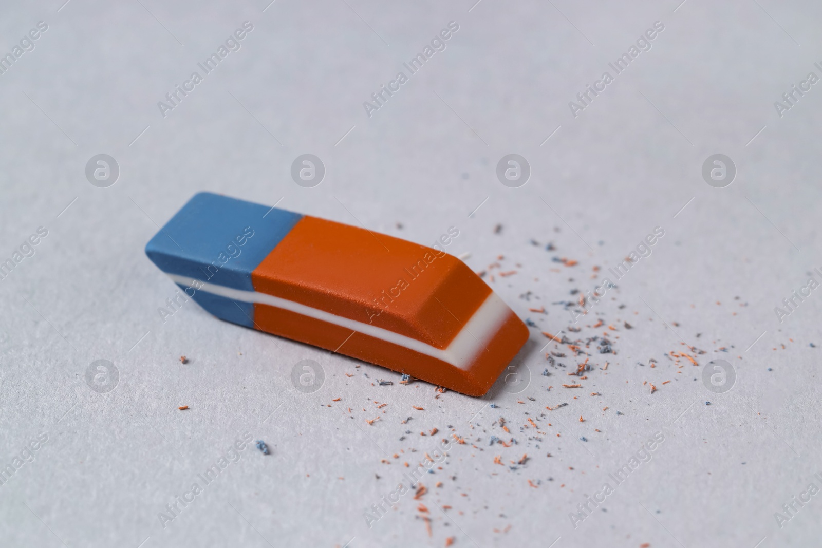 Photo of One eraser and scraps on grey background, closeup