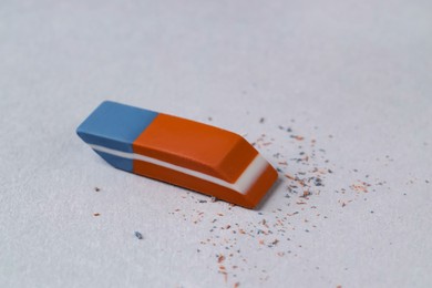 Photo of One eraser and scraps on grey background, closeup