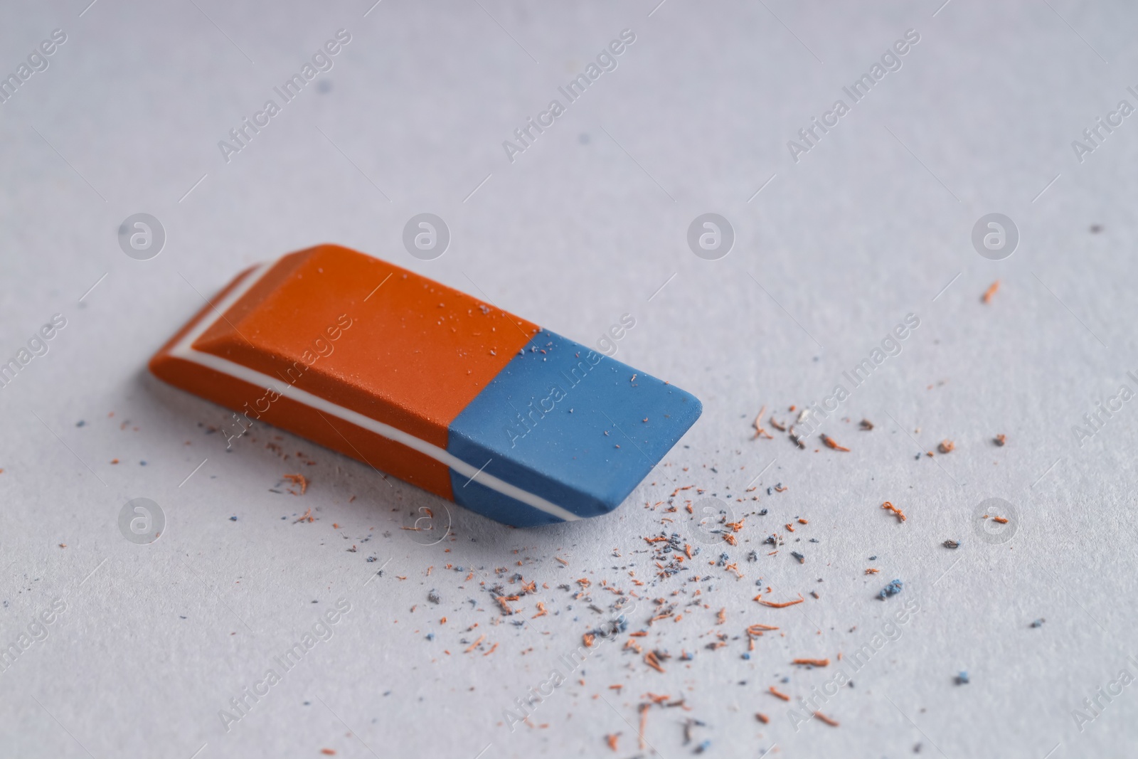 Photo of One eraser and scraps on grey background, closeup