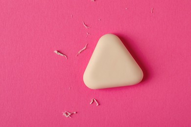 Photo of One eraser and scraps on pink background, top view