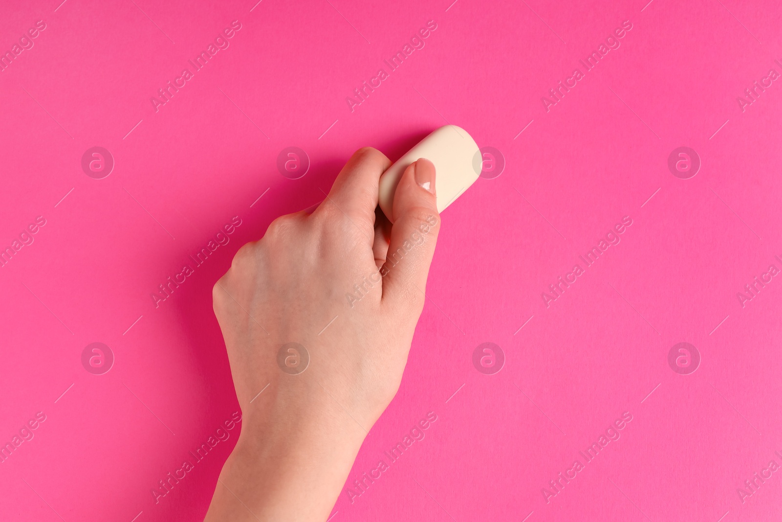 Photo of Woman using eraser on pink background, closeup