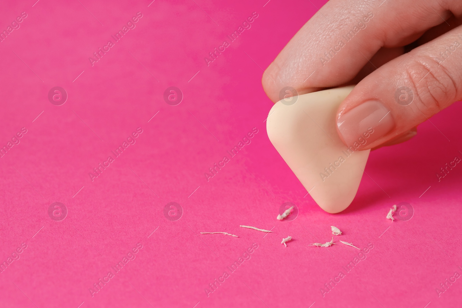 Photo of Woman using eraser on pink background, closeup. Space for text