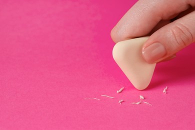 Photo of Woman using eraser on pink background, closeup. Space for text