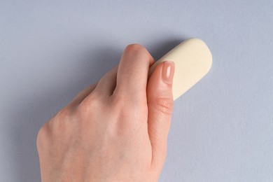 Photo of Woman using eraser on grey background, closeup