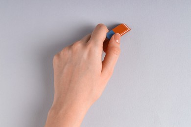 Photo of Woman using eraser on grey background, closeup