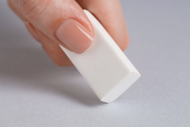 Photo of Woman using eraser on grey background, closeup