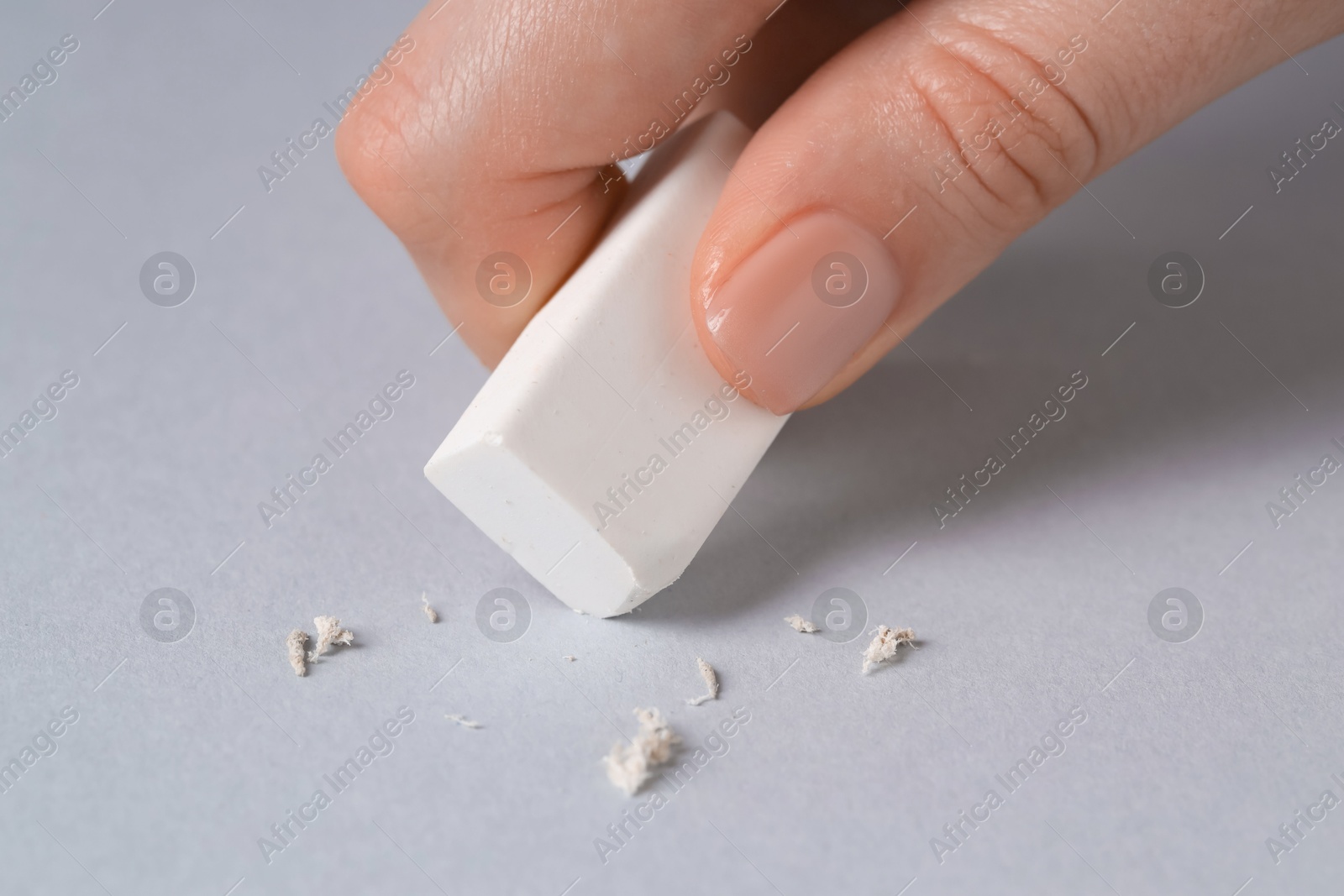 Photo of Woman using eraser on grey background, closeup