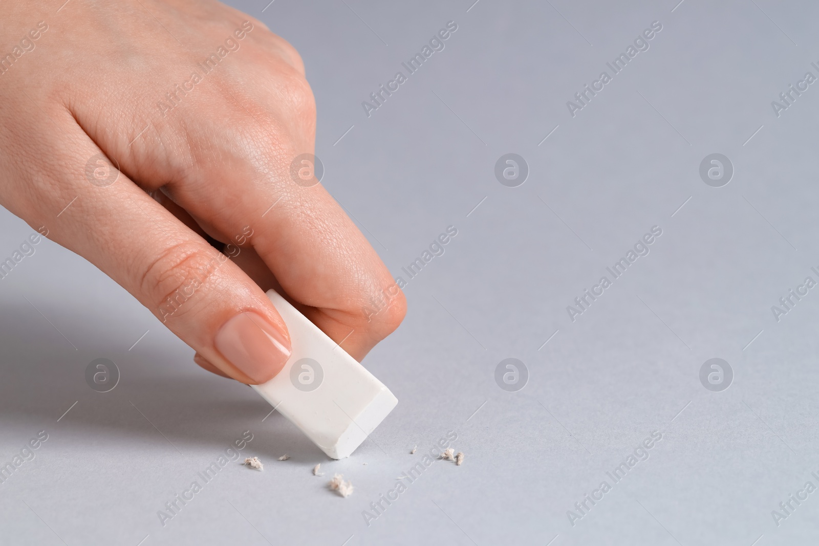 Photo of Woman using eraser on grey background, closeup. Space for text