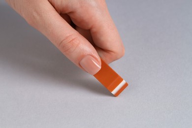 Photo of Woman using eraser on grey background, closeup