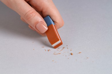 Photo of Woman using eraser on grey background, closeup