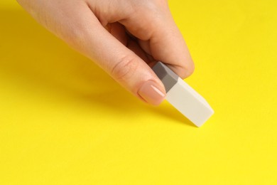 Photo of Woman using eraser on yellow background, closeup