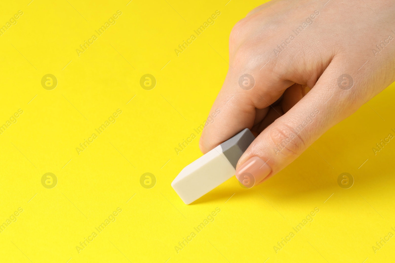 Photo of Woman using eraser on yellow background, closeup. Space for text