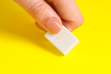 Photo of Woman using eraser on yellow background, closeup