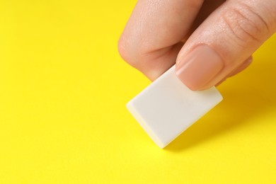 Photo of Woman using eraser on yellow background, closeup. Space for text