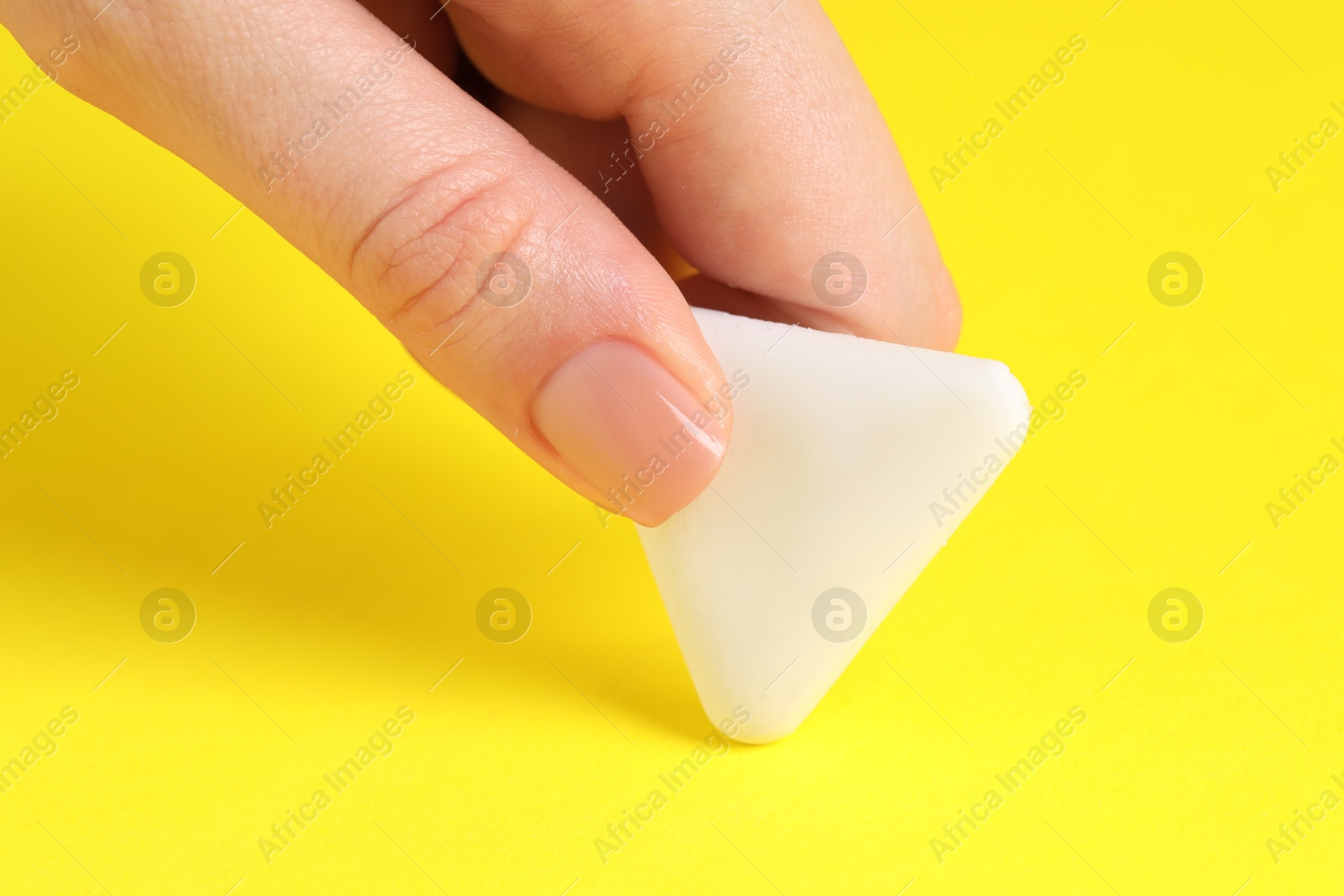 Photo of Woman using eraser on yellow background, closeup