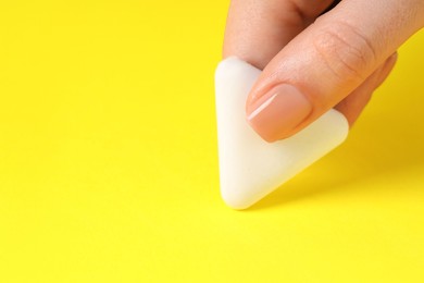 Photo of Woman using eraser on yellow background, closeup. Space for text