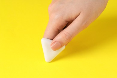 Photo of Woman using eraser on yellow background, closeup