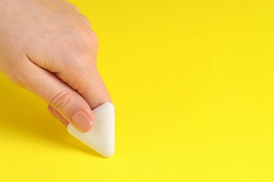 Photo of Woman using eraser on yellow background, closeup. Space for text