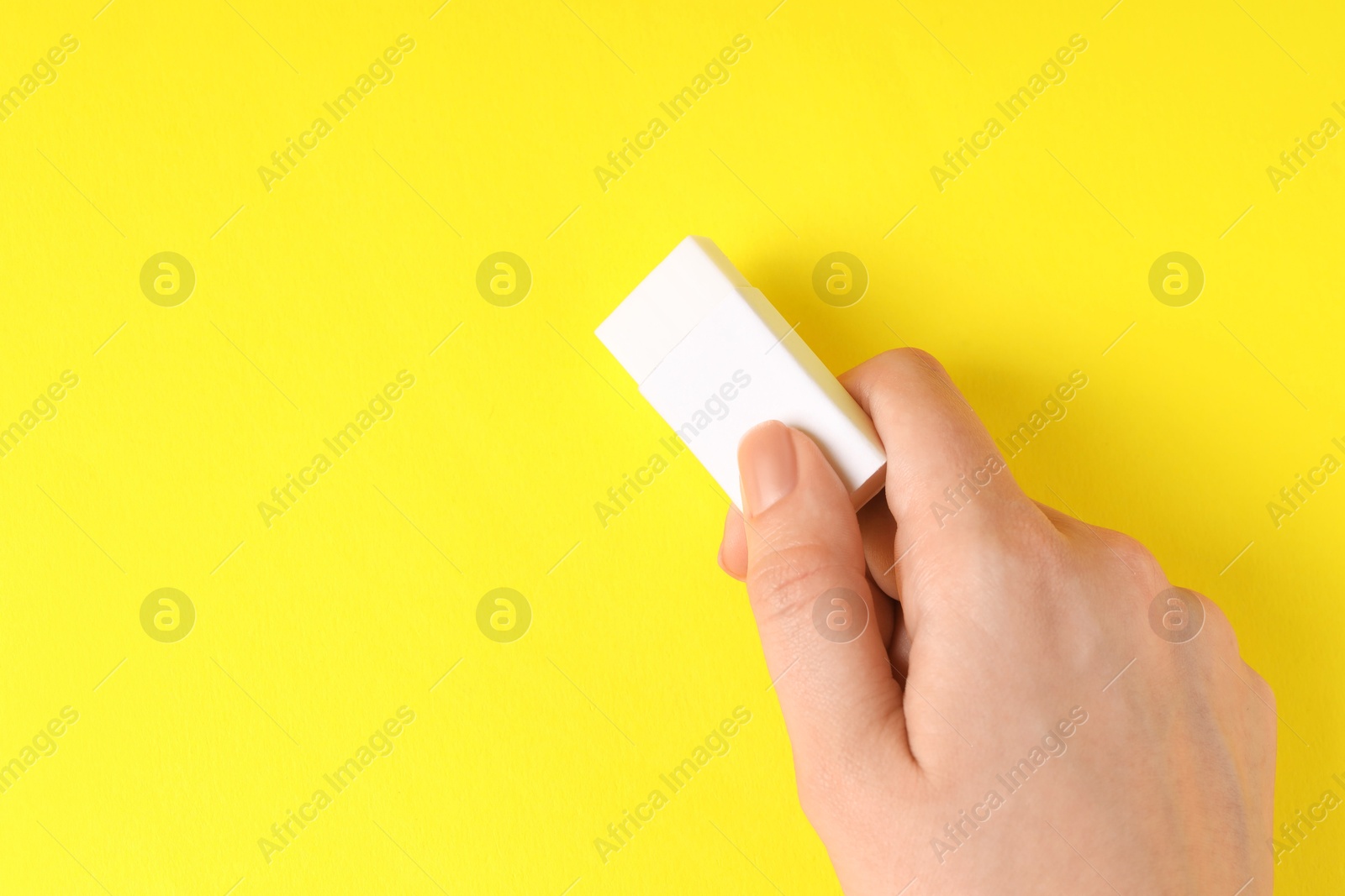 Photo of Woman using eraser on yellow background, closeup. Space for text