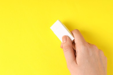 Photo of Woman using eraser on yellow background, closeup. Space for text