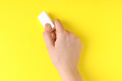 Photo of Woman using eraser on yellow background, closeup