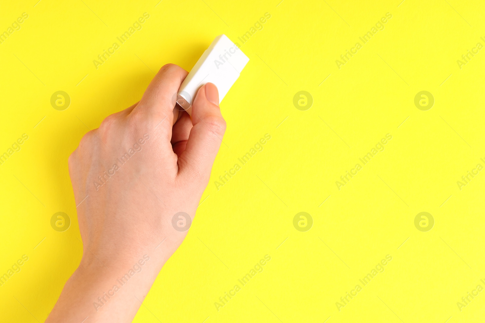 Photo of Woman using eraser on yellow background, closeup. Space for text