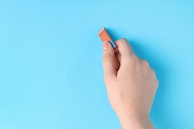 Photo of Woman using eraser on light blue background, closeup. Space for text