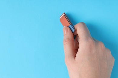 Photo of Woman using eraser on light blue background, closeup. Space for text