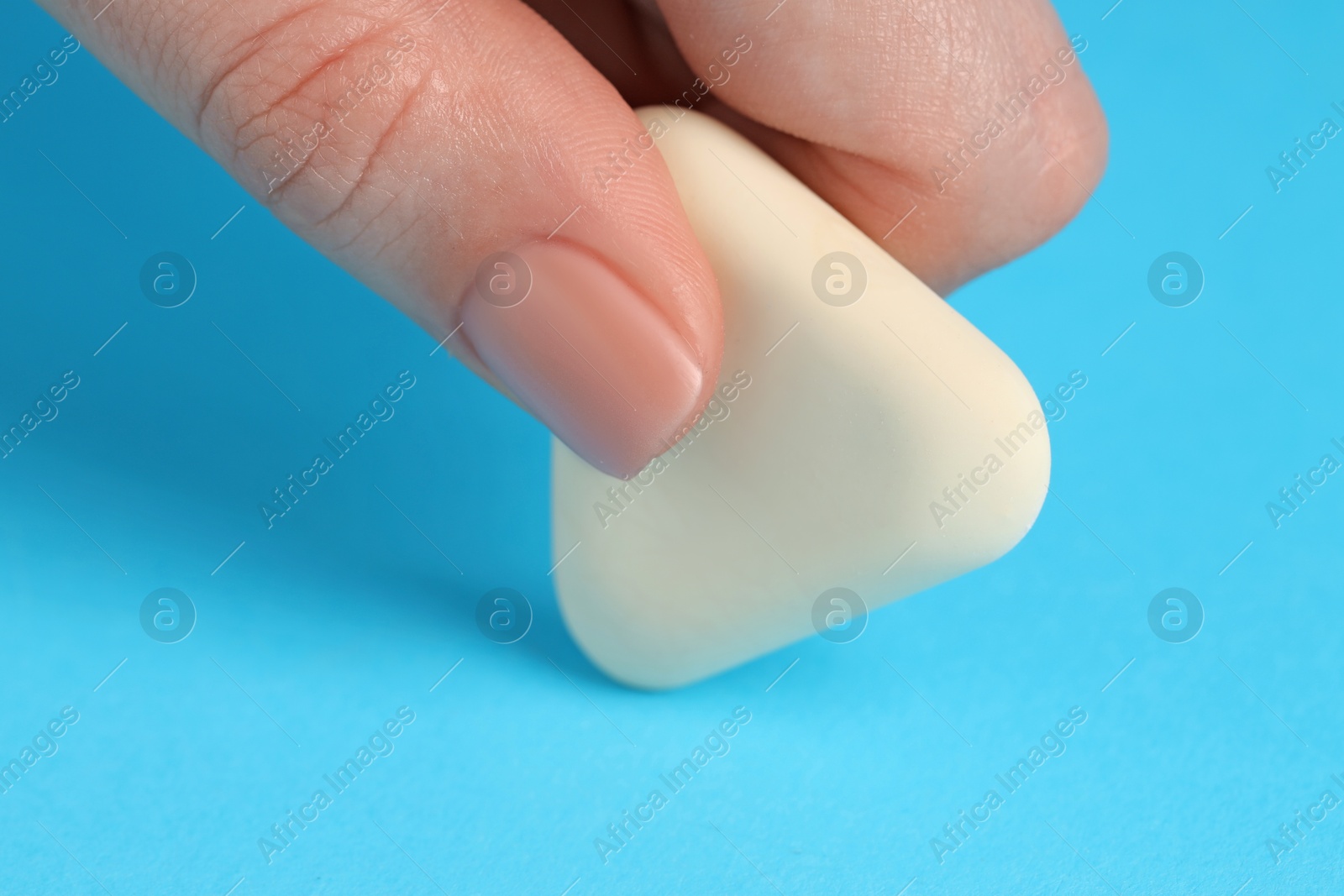 Photo of Woman using eraser on light blue background, closeup