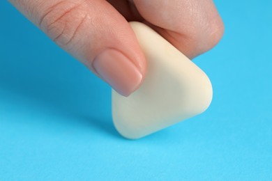 Photo of Woman using eraser on light blue background, closeup