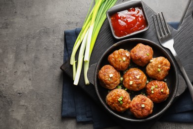 Photo of Tasty meatballs in baking dish served on grey table, flat lay. Space for text