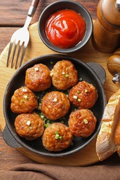 Photo of Tasty meatballs with green onion in baking dish served on wooden table, flat lay