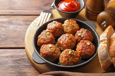 Photo of Tasty meatballs with green onion in baking dish served on wooden table