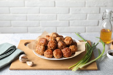 Photo of Many delicious meatballs, green onion and garlic on light textured table