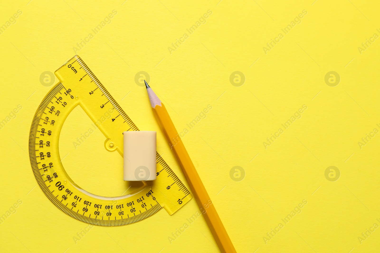 Photo of Eraser, pencil and protractor on yellow background, top view. Space for text