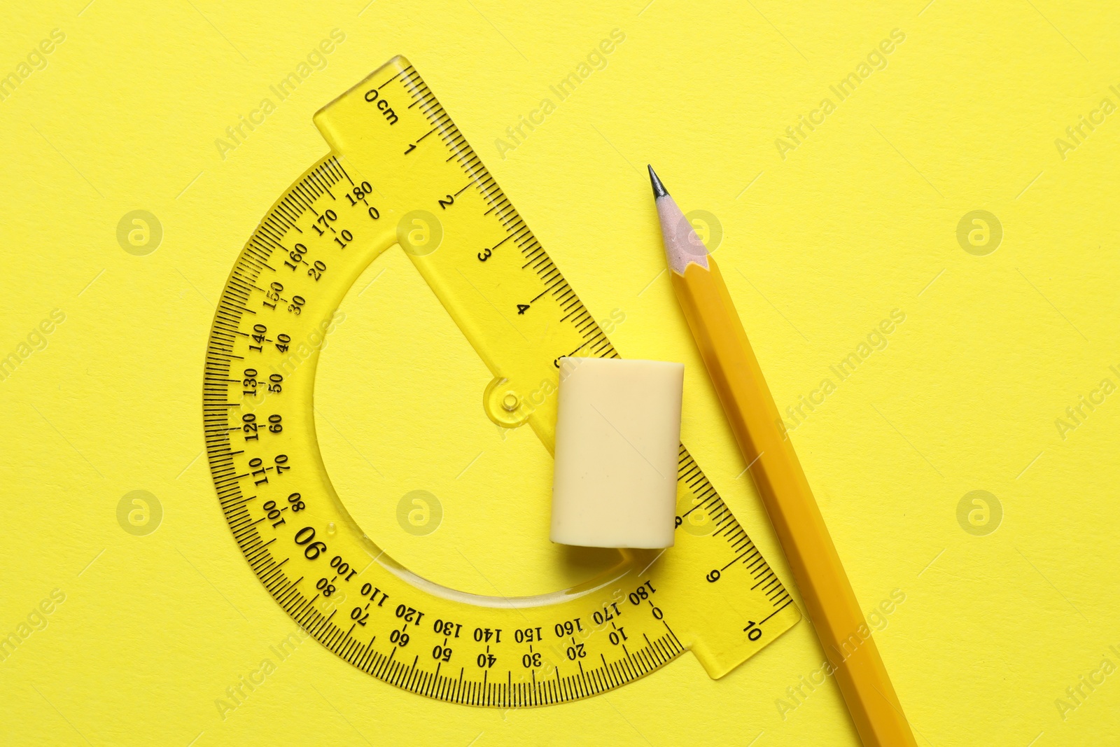 Photo of Eraser, pencil and protractor on yellow background, top view