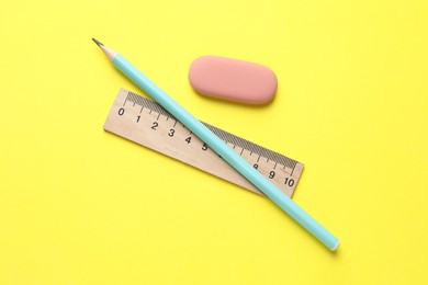 Photo of Eraser, pencil and ruler on yellow background, top view