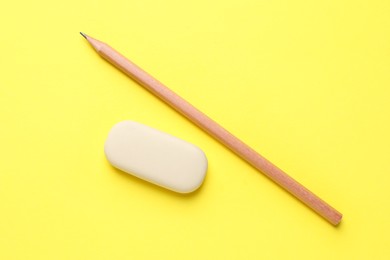 Photo of Eraser and pencil on yellow background, top view