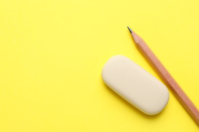 Photo of Eraser and pencil on yellow background, top view. Space for text