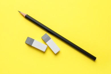 Photo of Erasers and pencil on yellow background, top view