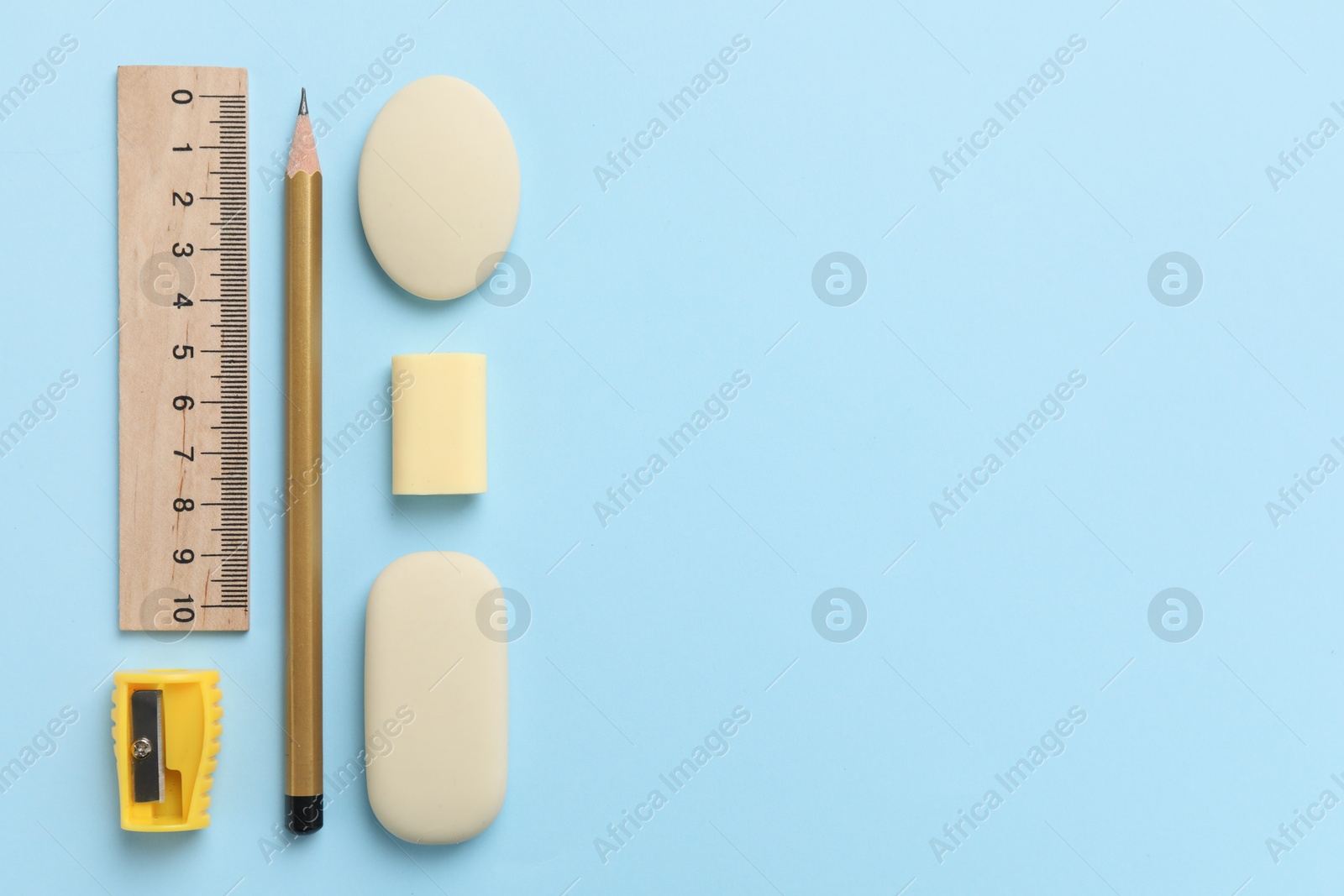 Photo of Erasers and other stationery on light blue background, flat lay. Space for text