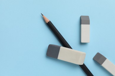 Photo of Erasers and pencil on light blue background, top view. Space for text