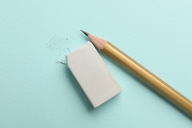 Photo of Eraser and pencil on light blue background, top view