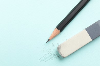 Photo of Eraser and pencil on light blue background, top view. Space for text